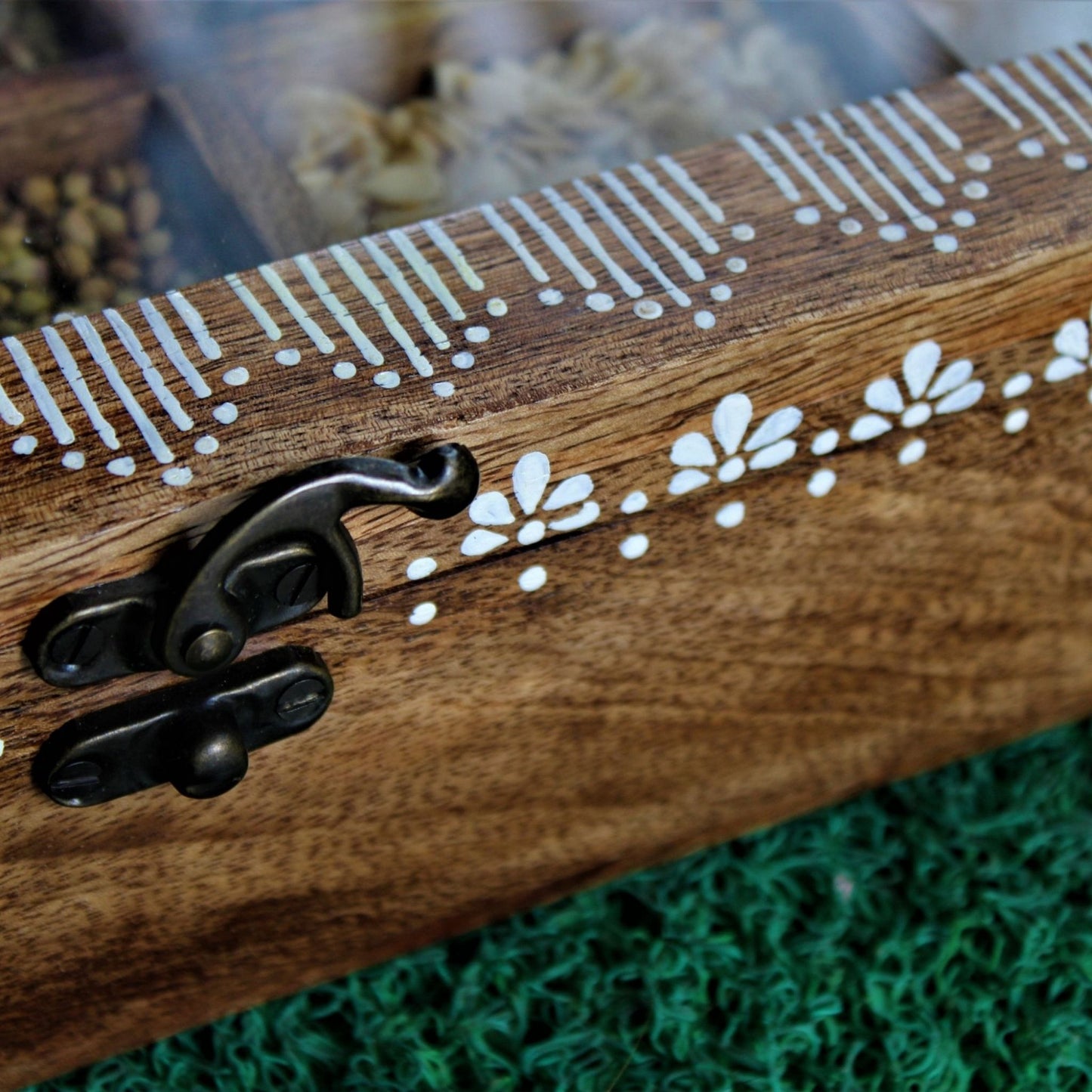 Handcrafted and Hand Painted Mango Wood Spice box with 12 large partitions and glass top. Brass Lock and Aipan Design can be seen closely in the image.