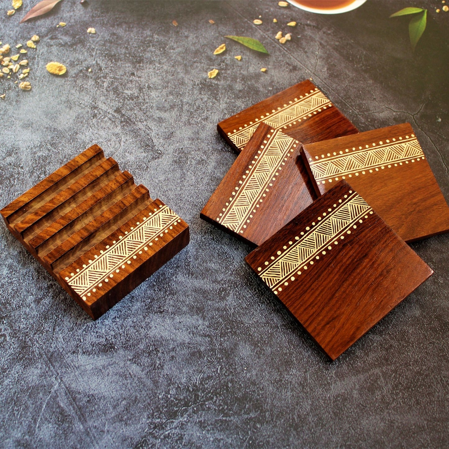 Indian Rosewood Hand Painted and Well Finished Coaster Set with Stand. It is a set of four coasters with hand painted aipan inspired design on them.