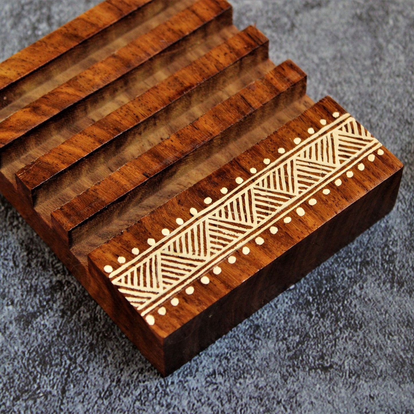 Indian Rosewood Hand Painted and Well Finished Coaster Set with Stand. It is a set of four coasters with hand painted aipan inspired design on them.