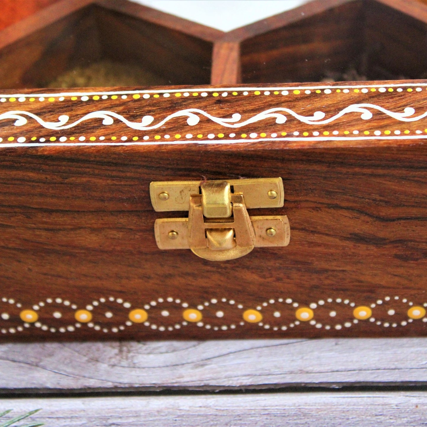 Aipan Inspired Hand Painted and Handcrafted Wooden Spice Storage Box with Glass Top and Free Wooden Spoon. Showcase Your Spices and other condiments with style. Alternatively Store Tea Bags, Dry Fruits and other condiments of the kitchen. This one gives the close up of the hand painting and brass locking mechanism.