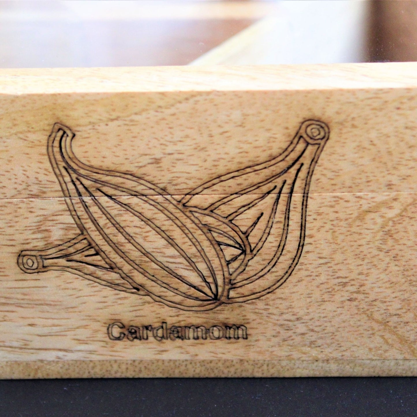 Spicy Bite Engraved Mango Wood Masala Dani or Indian Spice box with seven partitions in hexagon shape. This one shows the laser engraving done on the sides of the box.