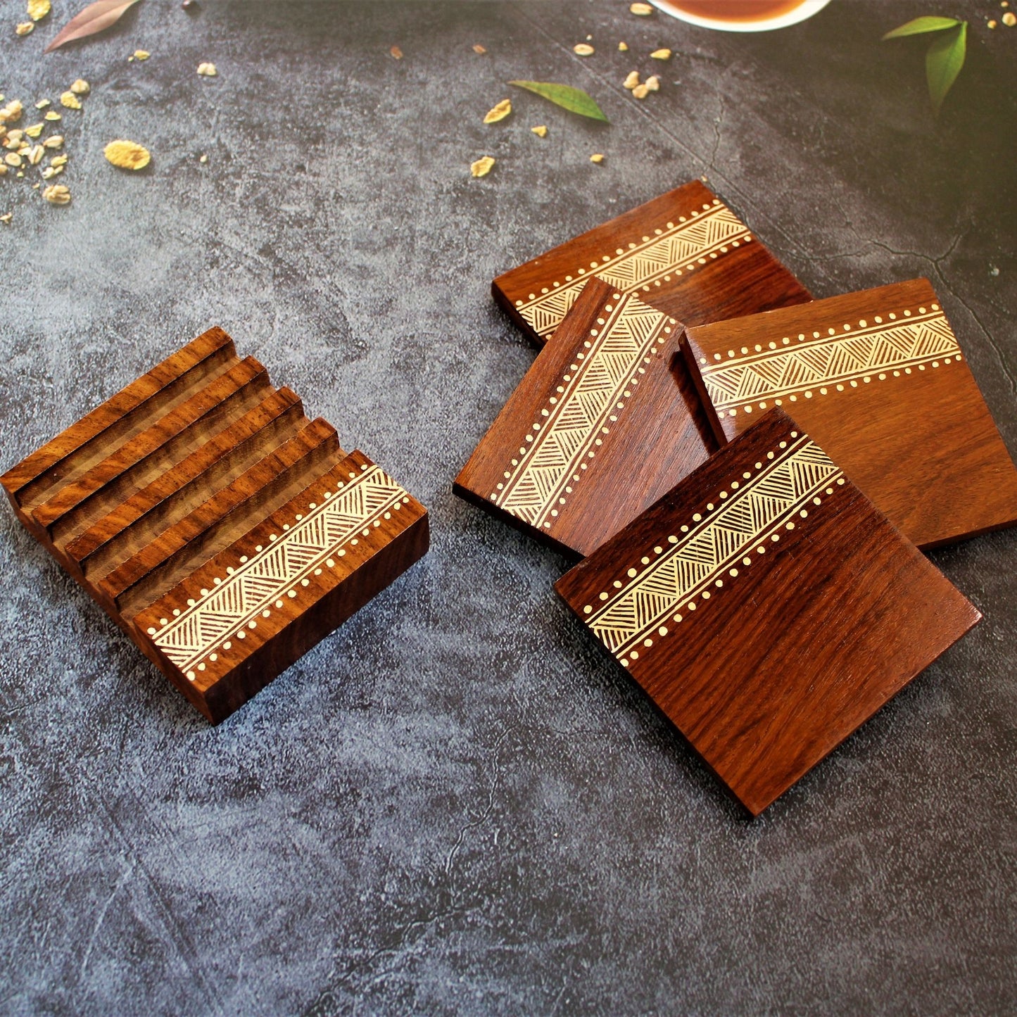 Indian Rosewood Hand Painted and Well Finished Coaster Set with Stand. It is a set of four coasters with hand painted aipan inspired design on them. 
